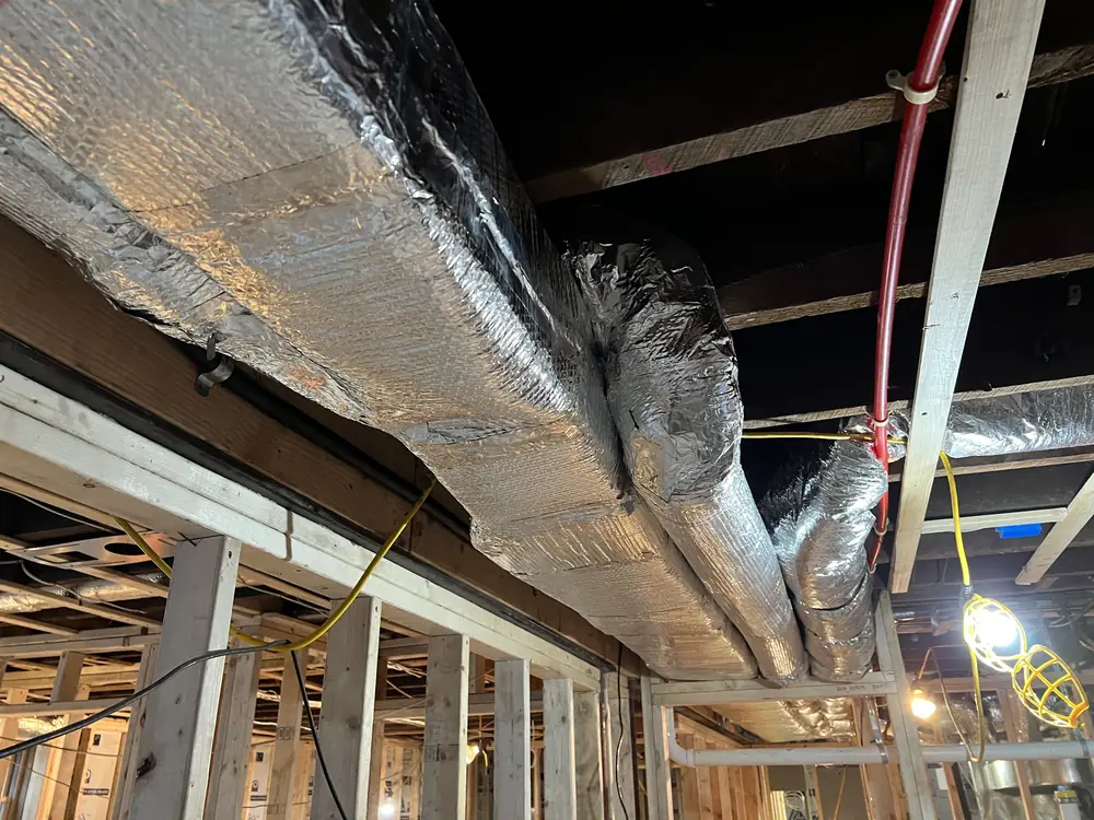 Multiple insulated duct runs and trunk line in a basement ceiling